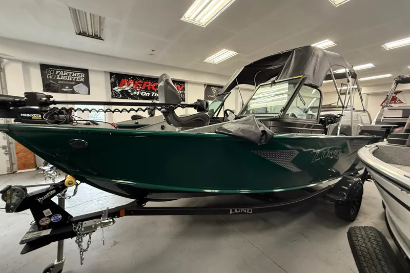 Slide: The Image of 2026 Lund 1775 Adventure Sport boat in showroom, featuring sleek design and Minn Kota trolling motor. - 15