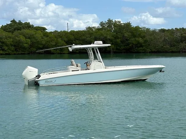 The Image of 2022 Boston Whaler DAUNTLESS boat on calm water with lush green trees in the background. - 0