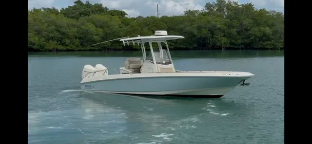 Slide: The Image of 2022 Boston Whaler DAUNTLESS boat cruising on calm water near lush greenery. - 2
