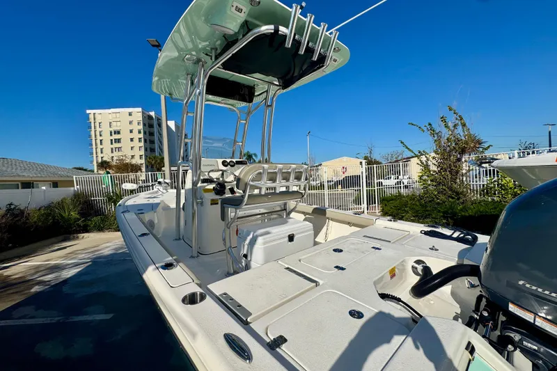 Slide: The Image of 2023 Key West 210 Bay Reef boat with T-top and outboard motor in a sunny marina. - 12