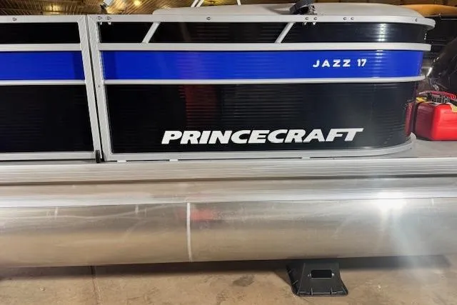Slide: The Image of 2026 Princecraft Jazz 170 pontoon boat with blue and black design in a garage. - 5