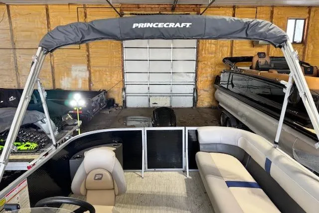 The Image of 2026 Princecraft Jazz 190-4S pontoon boat in a garage, featuring spacious seating and canopy. - 0