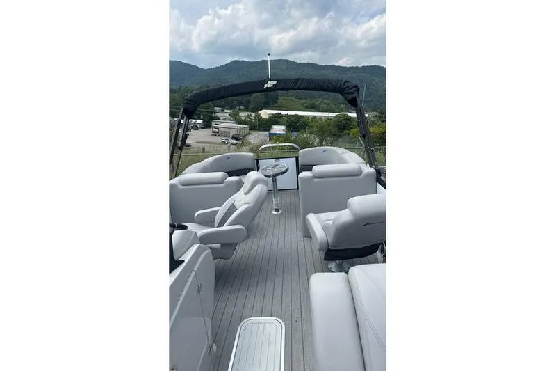 Slide: The Image of 2024 Starcraft SLS 3 pontoon boat interior with plush seating and scenic mountain backdrop. - 2