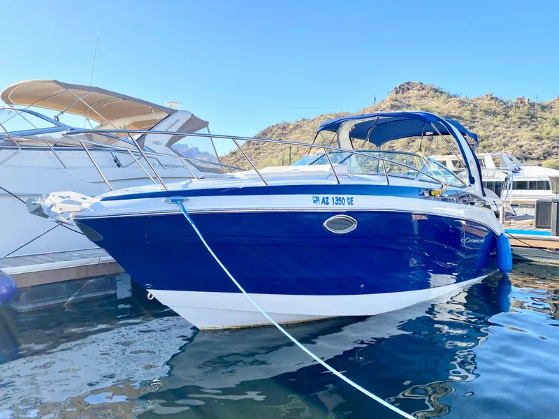 The Image of 2022 Crownline 264 CR boat docked in a marina, featuring a sleek blue and white design. - 0
