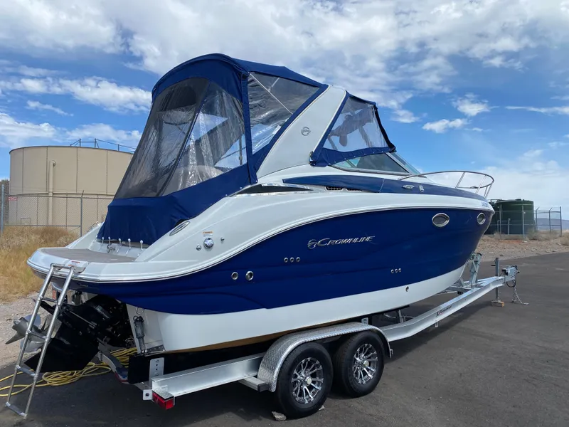 Slide: The Image of 2022 Crownline 264 CR boat on trailer, blue and white design, parked outdoors. - 3