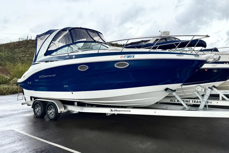 Slide: The Image of 2022 Crownline 264 CR boat on trailer, blue and white design, parked outdoors. - 40