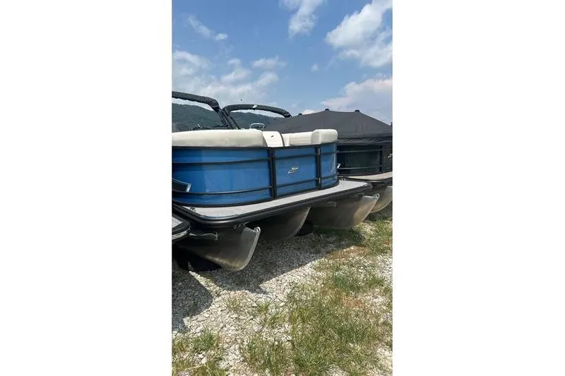 The Image of 2024 Starcraft EXS 3 pontoon boat, blue exterior, parked on gravel under a clear sky. - 0