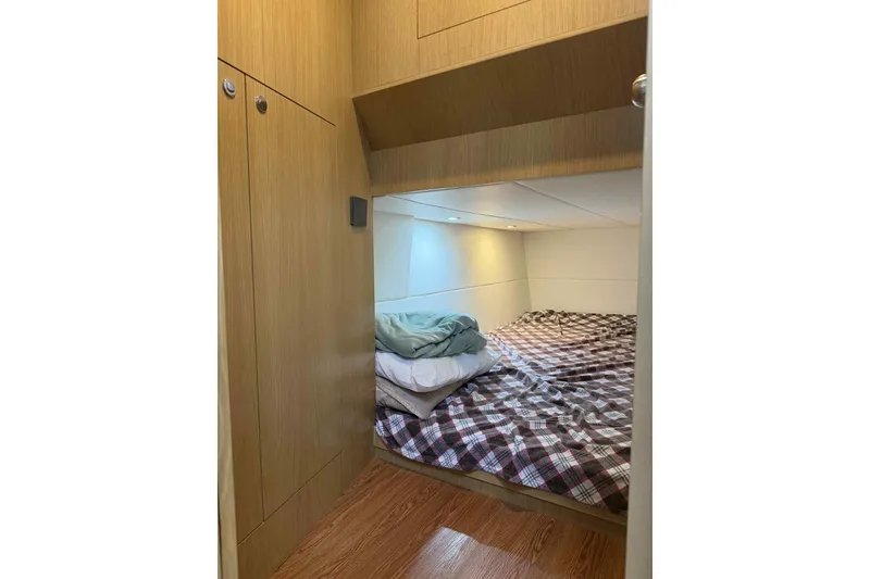 Slide: The Image of Cozy cabin interior of 2025 Bracewell Commander 36SF with plaid bedding and wooden cabinetry. - 18