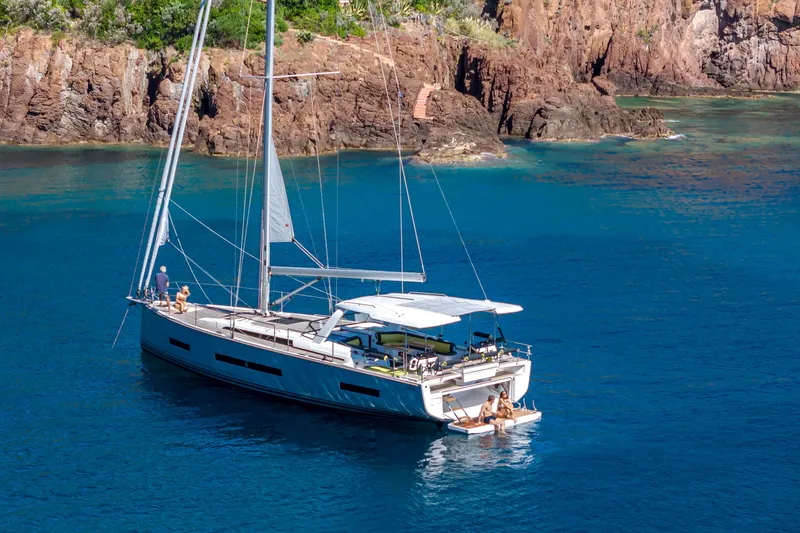 Slide: The Image of 2026 Hanse 590 yacht sailing near rocky coastline in clear blue waters. - 23