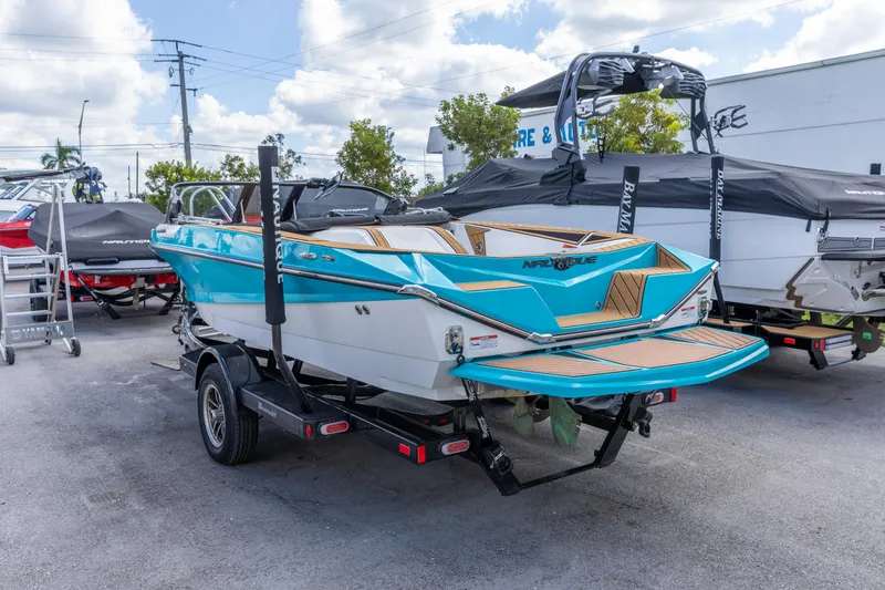 Slide: The Image of 2023 Nautique Ski Nautique boat on trailer, vibrant blue and white design. - 12
