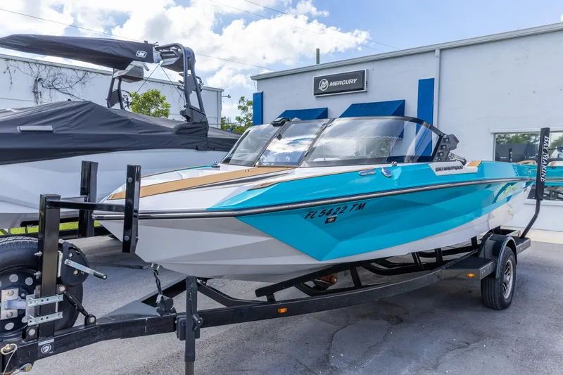 Slide: The Image of 2023 Nautique Ski Nautique boat on trailer, vibrant blue and white design. - 13