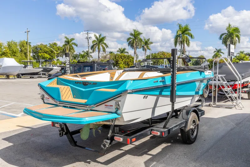 Slide: The Image of 2023 Nautique Ski Nautique boat on trailer, vibrant blue and white design, parked outdoors. - 14