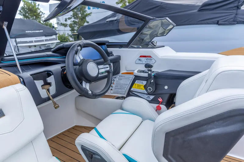 Slide: The Image of 2023 Nautique Ski Nautique boat interior with steering wheel and controls. - 2