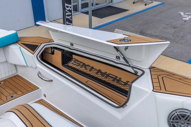 Slide: The Image of 2023 Nautique Ski Nautique boat storage compartment with open lid and teak flooring. - 22