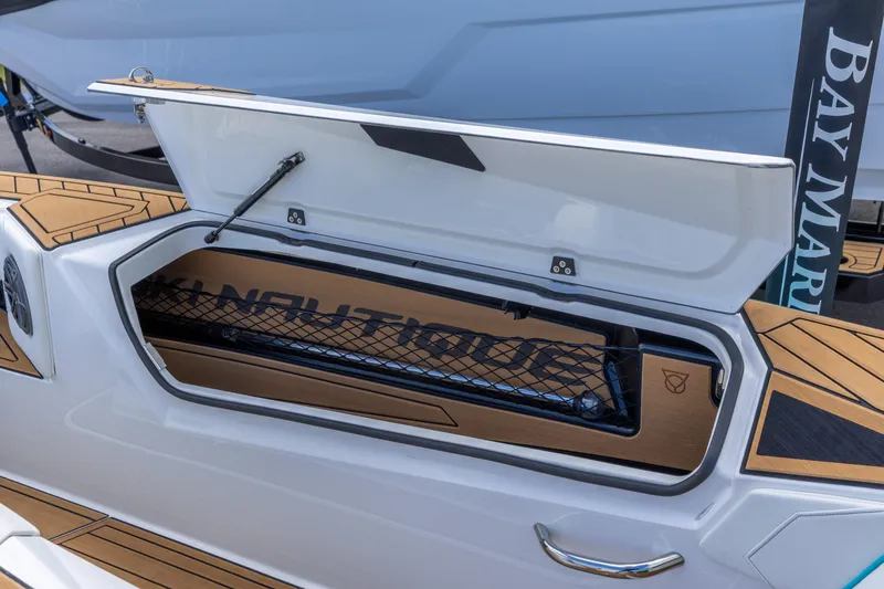 Slide: The Image of 2023 Nautique Ski Nautique boat storage compartment with open lid and netting. - 7