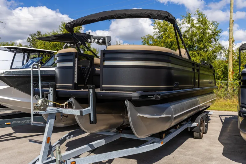 Slide: The Image of 2026 Viaggio Lago Z-S pontoon boat on trailer, parked outdoors under blue sky. - 23