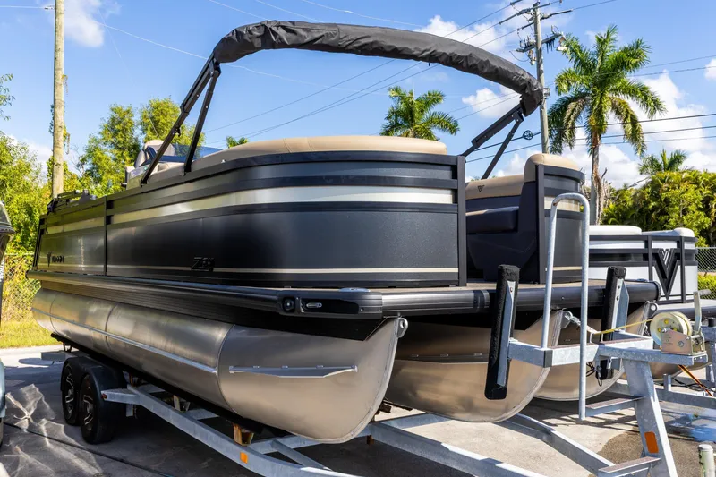 Slide: The Image of 2026 Viaggio Lago Z-S pontoon boat on trailer, sunny day, palm trees in background. - 24