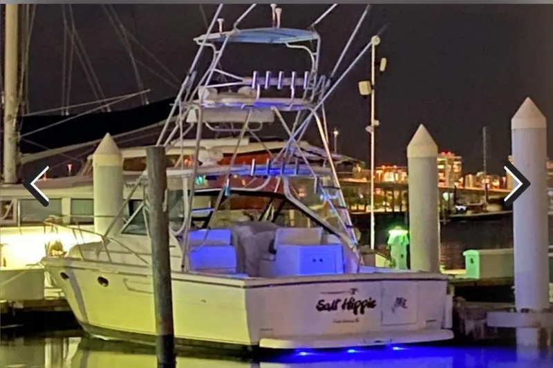 Slide: The Image of 1995 Tiara Yachts 3100 Open docked at night with blue underwater lights. - 14