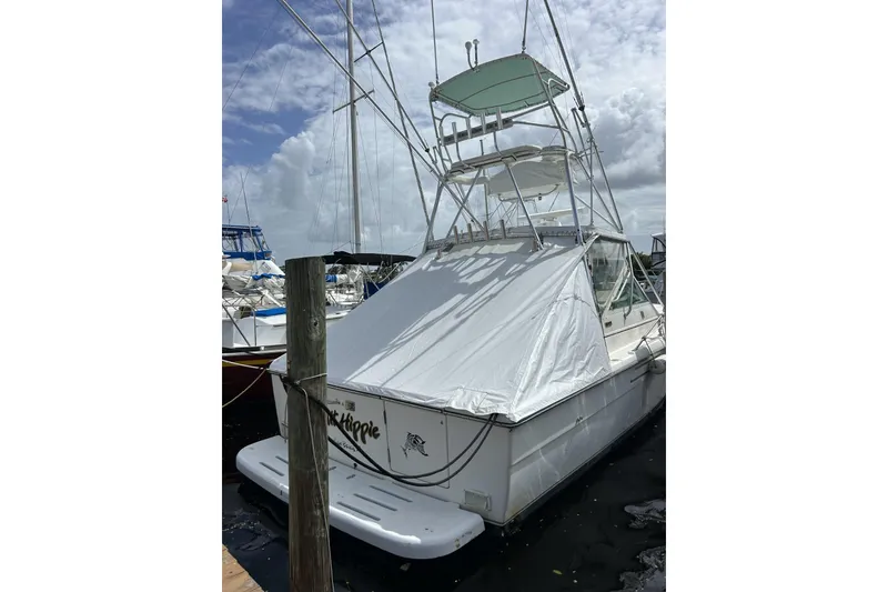 Slide: The Image of 1995 Tiara Yachts 3100 Open docked, featuring a white cover and fishing tower. - 15