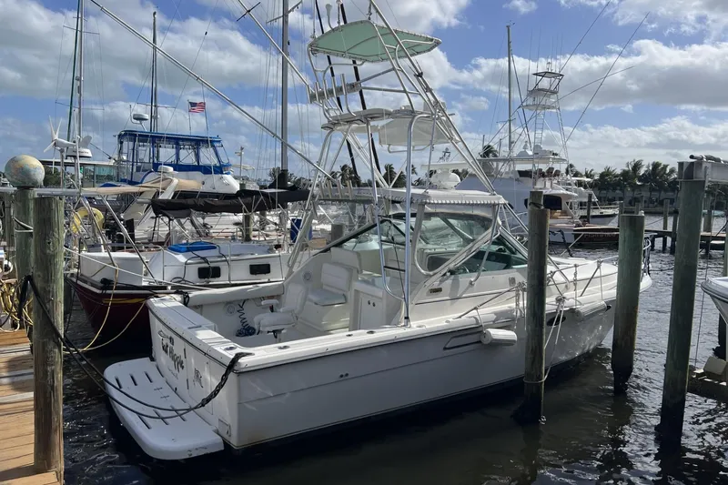 Slide: The Image of 1995 Tiara Yachts 3100 Open docked at marina, surrounded by other boats. - 2