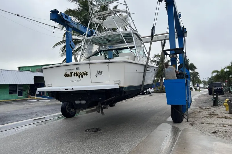 Slide: The Image of 1995 Tiara Yachts 3100 Open being lifted by a blue crane in a marina. - 5