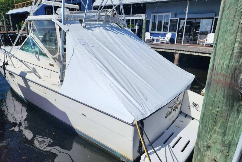 Slide: The Image of 1995 Tiara Yachts 3100 Open docked, covered with a protective tarp. - 6