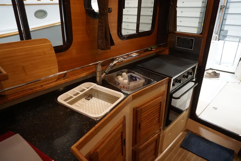Slide: The Image of 2013 Ranger Tugs S-31 boat kitchen with sink, stove, and wooden cabinetry. - 27