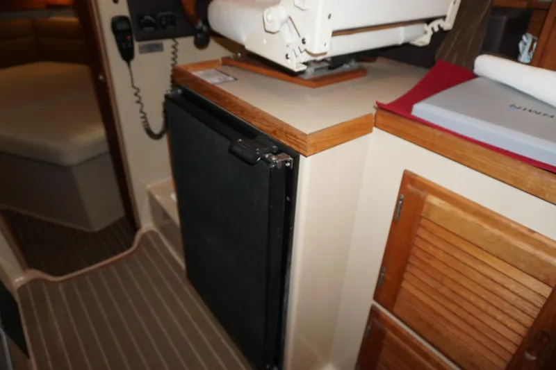 Slide: The Image of Interior of 2013 Ranger Tugs S-31 showing compact kitchen area with fridge and wooden cabinets. - 35