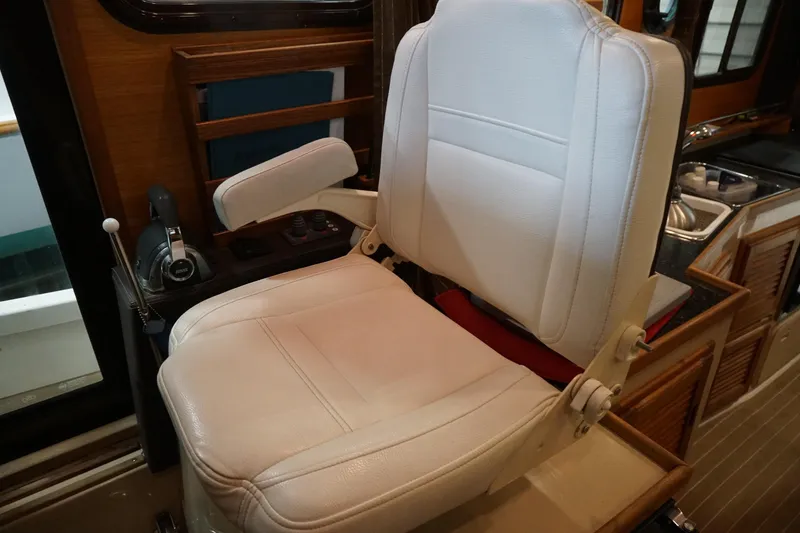 Slide: The Image of Captain's chair in 2013 Ranger Tugs S-31 boat interior, featuring white upholstery and control panel. - 37