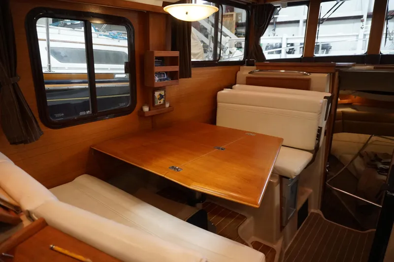 Slide: The Image of 2013 Ranger Tugs S-31 interior with wooden dining table and cushioned seating. - 38