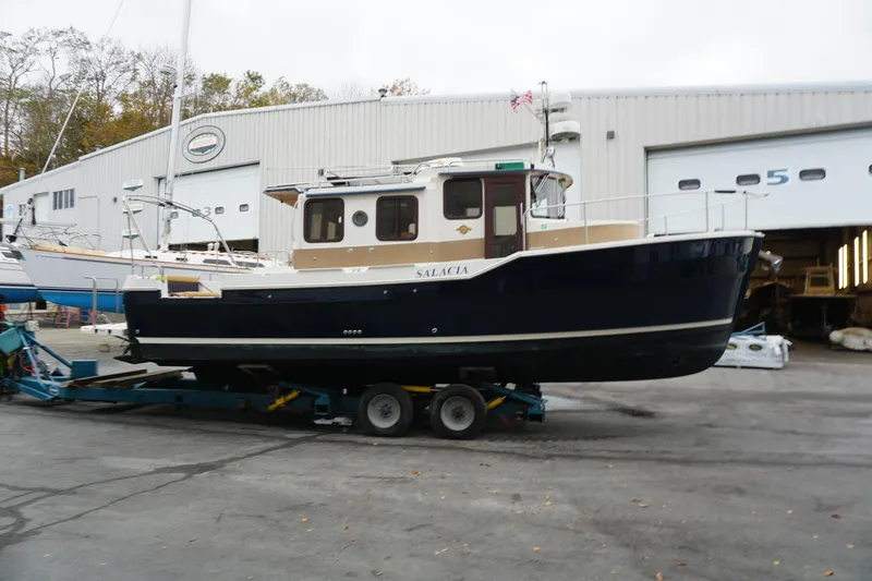 Slide: The Image of 2013 Ranger Tugs S-31 boat on trailer outside a large garage. - 6