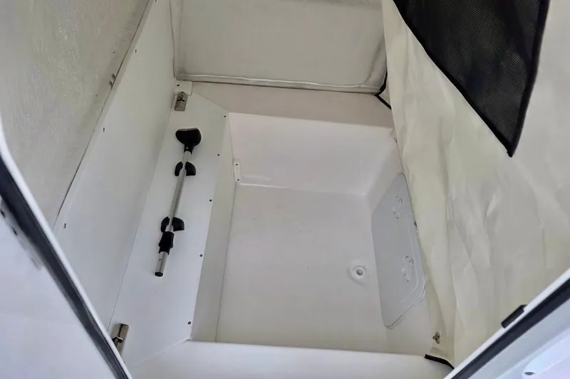 Slide: The Image of 2026 Sea Fox 231 Bay Fox storage compartment with white interior and mounted rod holder. - 8