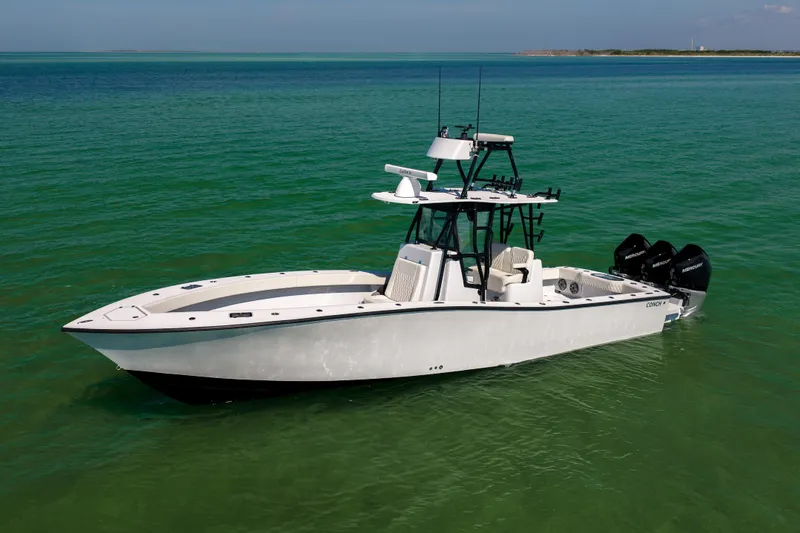 Slide: The Image of 2025 Conch 33 boat on clear green water, featuring triple outboard engines. - 13