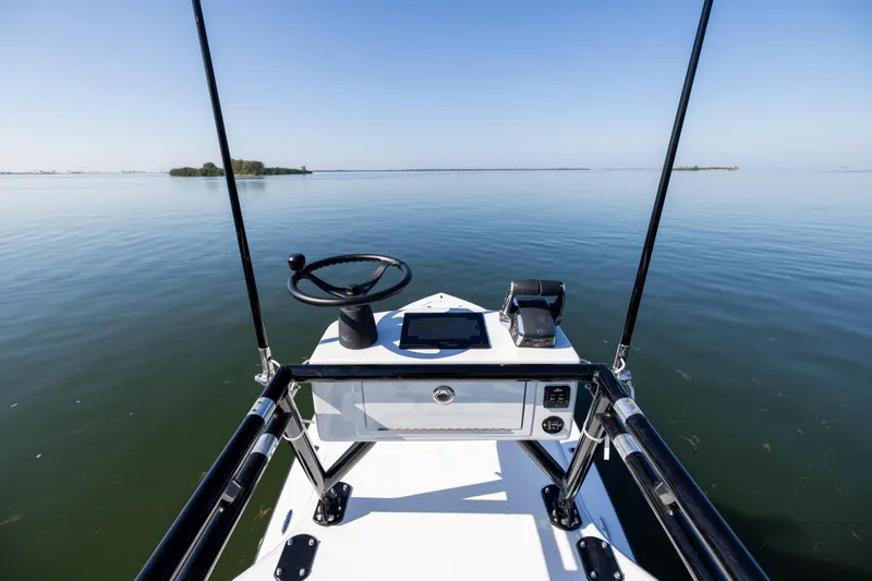 Slide: The Image of 2025 Conch 33 boat helm on calm water, clear sky, and distant islands. - 48