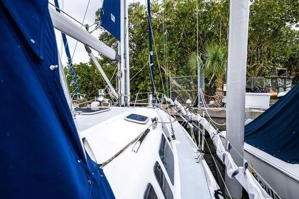 Slide: The Image of 2001 Hunter 340 sailboat docked, featuring blue sails and lush greenery in the background. - 27
