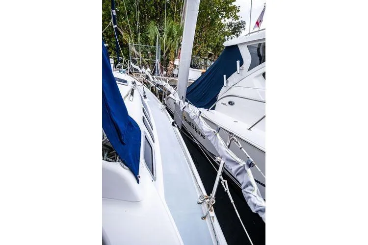 Slide: The Image of Sailboat docked at marina, Hunter 340 model, 2001, with blue covers and nearby trees. - 28