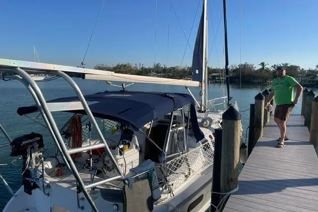 Slide: The Image of 2001 Hunter 340 sailboat docked with a person standing nearby on a sunny day. - 34