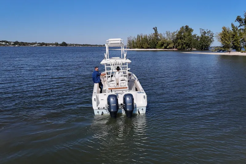 Slide: The Image of 2018 Sailfish 270 CC boat cruising on a calm lake near a wooded shoreline. - 12