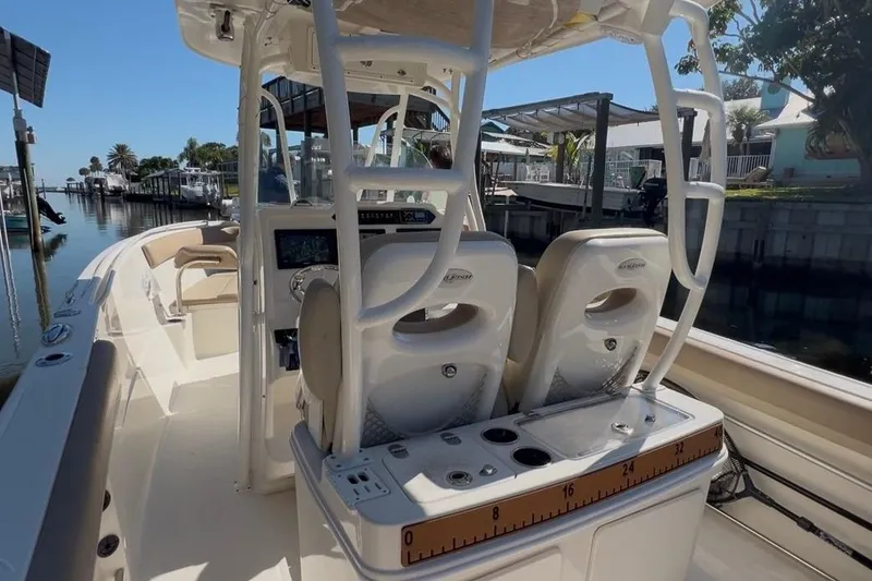 Slide: The Image of 2018 Sailfish 270 CC boat interior with dual seats and console, docked by a canal. - 24