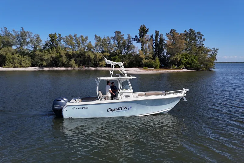 Slide: The Image of 2018 Sailfish 270 CC boat on calm water near a wooded shoreline. - 5