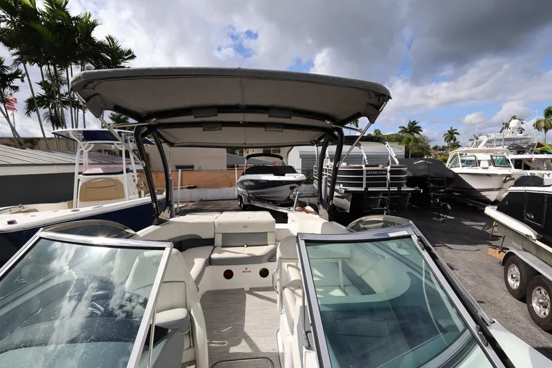 Slide: The Image of 2022 Cobalt 220S boat with canopy, parked among other boats under a cloudy sky. - 17