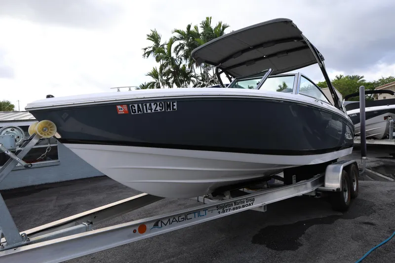Slide: The Image of 2022 Cobalt 220S boat on trailer, parked outdoors with palm trees in background. - 2