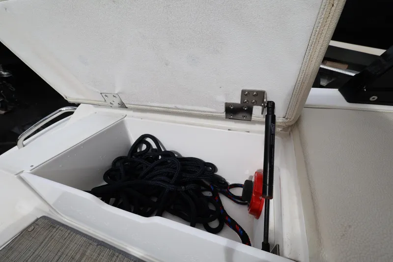 Slide: The Image of Open storage compartment on 2022 Cobalt 220S boat with coiled rope inside. - 23