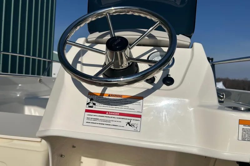 Slide: The Image of Steering wheel of 2026 Boston Whaler 160 Super Sport boat, featuring warning labels. - 11