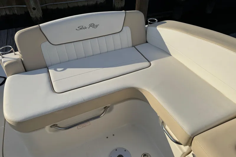 Slide: The Image of 2013 Sea Ray 280 Sundancer boat seating area with beige upholstery and logo. - 10