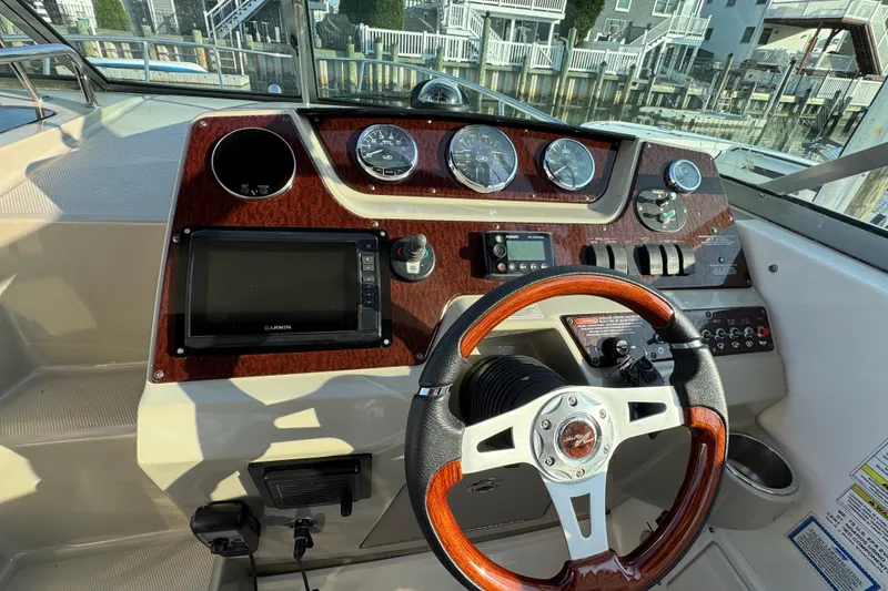 Slide: The Image of Dashboard of a 2013 Sea Ray 280 Sundancer boat with steering wheel and gauges. - 18