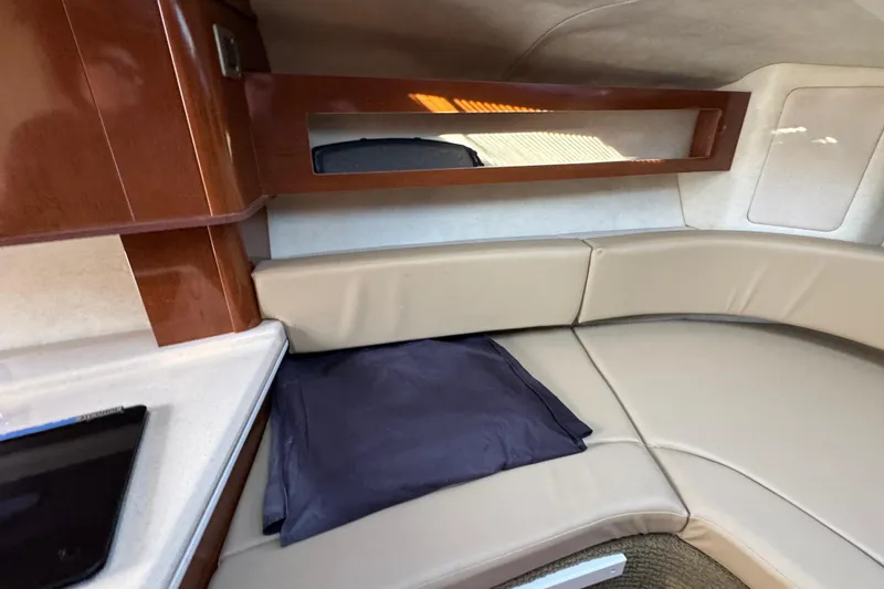 Slide: The Image of 2013 Sea Ray 280 Sundancer cabin interior with beige seating and wooden accents. - 25