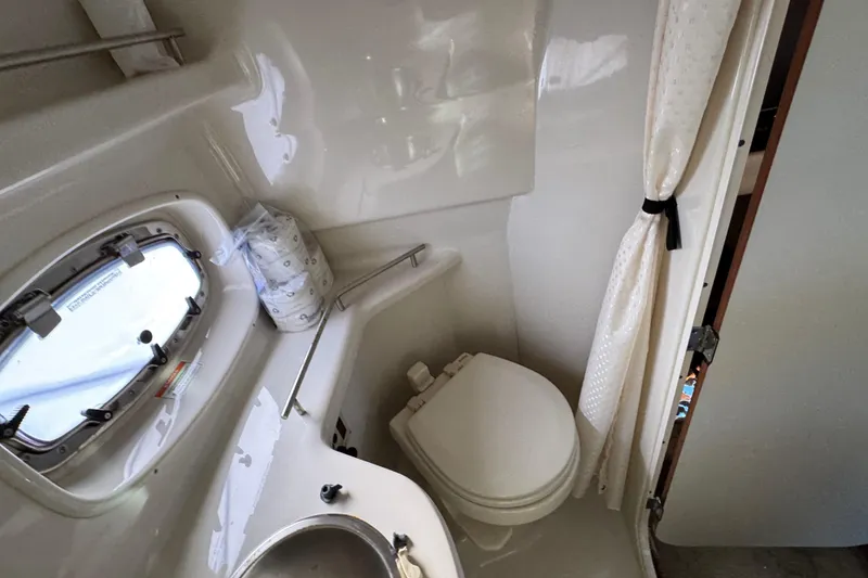 Slide: The Image of 2013 Sea Ray 280 Sundancer bathroom with toilet, sink, and porthole window. - 30