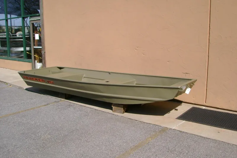 Slide: The Image of 2026 Tracker Grizzly 15 Jon boat displayed outdoors on wooden blocks. - 3