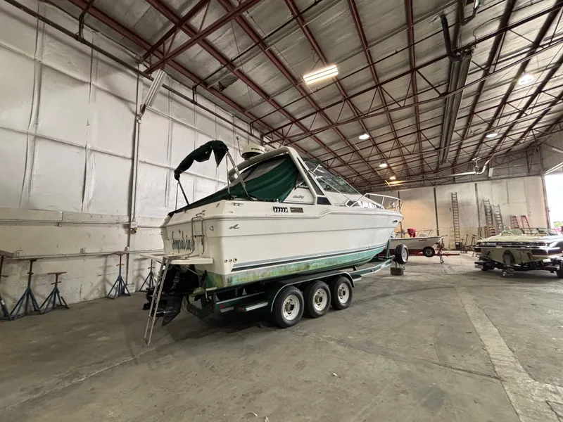 Slide: The Image of 1989 Sea Ray 290 Sundancer boat on trailer in spacious indoor storage facility. - 4